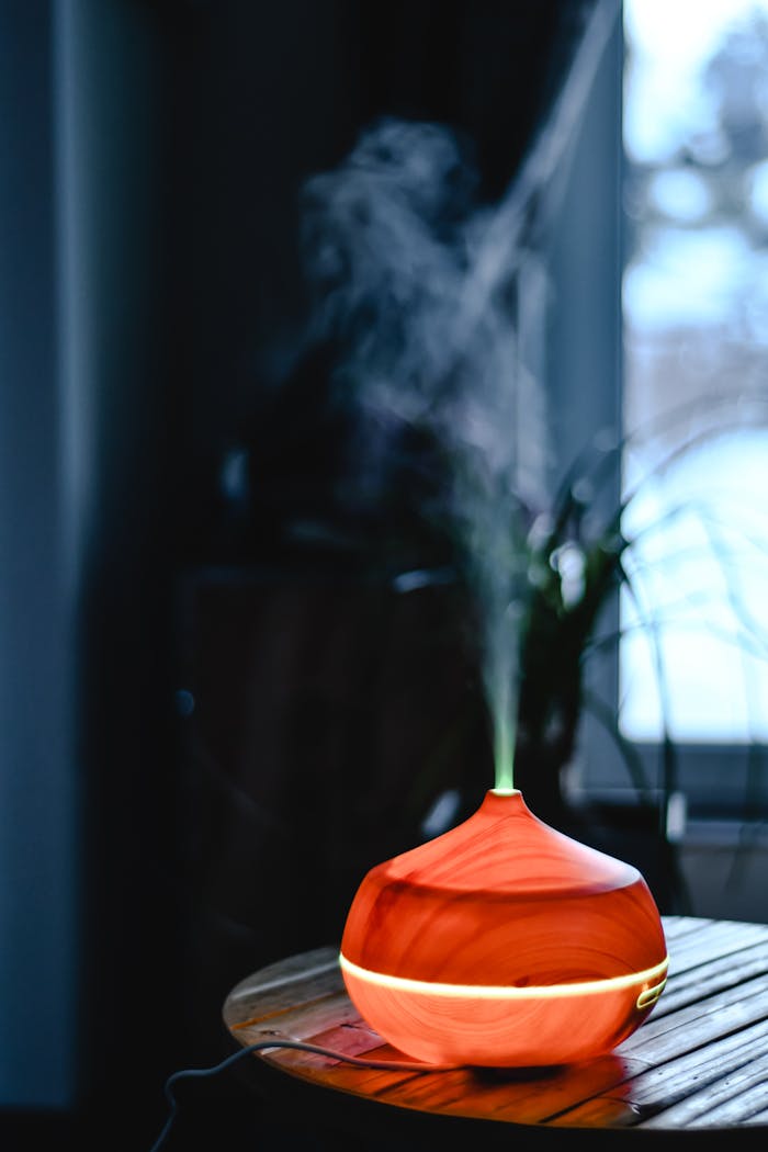 hero-img-01 An aromatic wooden diffuser releasing smoke, creating a calm indoor atmosphere near a window.